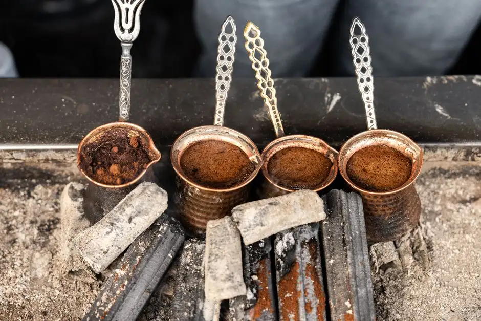 Four cezve pots brewing authentic Turkish coffee over sand in Istanbul, Turkey.