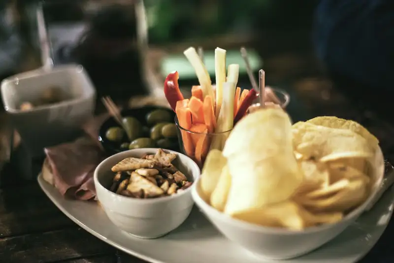 A tempting snack platter featuring crisps, vegetables, and olives, perfect for a casual gathering.