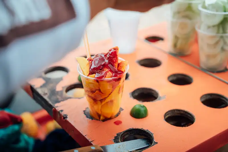 Vibrant street food scene with sliced mango topped with syrup, captured in Ciudad de México.